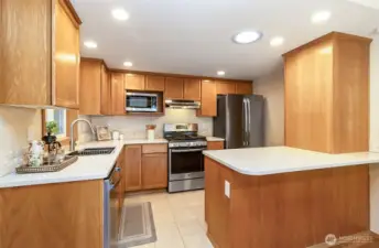SS appliances and quartz countertops with tile accents