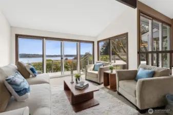 From this corner, it becomes clear just how much glass this space really has. Windows wrap around the living room, flanking the large sliding door and continuing onto the adjacent wall, creating a wide, uninterrupted sweep of the deck and water beyond. It’s layered, not just one focal point, but multiple angles that keep pulling your eye outward. You even catch the upper windows from the dining area above, adding another dimension of light and connection between spaces. While this isn’t direct waterfront, the view absolutely delivers, giving you that open, expansive feel without the maintenance that sometimes comes with it.