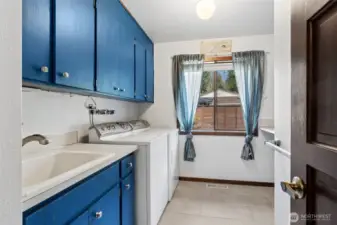 This laundry room leans into function in a way you don’t see as often anymore. At roughly 9½ by 10½ feet, it’s noticeably larger than the typical pass-through setup, giving you real space to work. The tile floor is ready for anything, and the royal blue cabinetry adds a pop of personality while keeping storage tucked neatly away. A utility sink makes cleanup easy, especially for those messier tasks, and the folding counter off to the side is exactly what you want when sorting or tackling laundry day. There’s also a large operable window overlooking the front yard, bringing in light and fresh air when you need it.