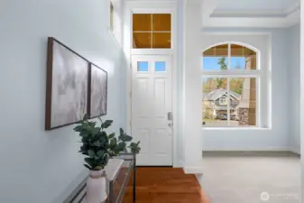 Bright, welcoming entryway with soaring windows that fill the space with natural light, opening gracefully to an adjacent formal living area.