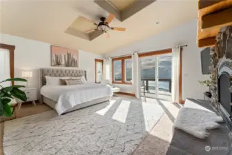 View 1 of upper level Primary Bedroom 1 w/ fireplace, vaulted ceilings, skylights, walk-in closet and glass sliding doors leading to the waterfront view deck.