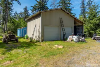 The two car garage with a carport and one of five sheds in the back.