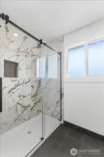 Primary bathroom with oversized walk in shower with gorgeous tile work and tile flooring.