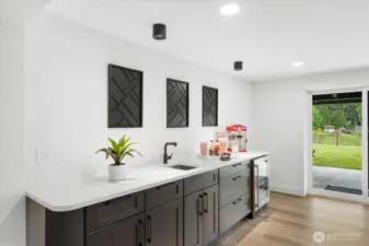 Wet bar in game room with beverage fridge and room for a full sized fridge.
