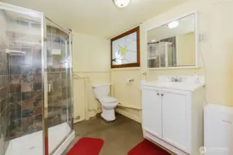 Downstairs bathroom with tiled shower stall and pretty stained glass for natural light from laundry room.