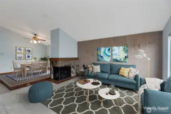 Virtually staged living room with wood-burning fireplace and adjoining dining room