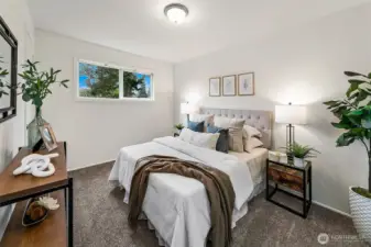 A comfortable main-level bedroom with south-facing windows overlooking the private backyard, filling the space with natural light throughout the day.