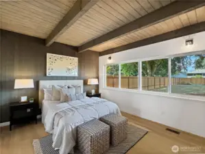 The spacious primary suite has a full wall of windows overlooking the serene park like setting of the back yard.