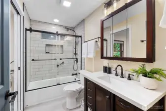 The main floor bath was fully updated in 2024 with a new tub, sink, toilet, cabinets, and faucets, all thoughtfully coordinated with the finishes in the kitchen and primary bath. Modern subway tile with niche detailing complements the sleek glass shower doors, while matte black and espresso fixtures are carried consistently throughout the home, including door hardware. Vanity lighting with see-through glass and Edison style elements along with recessed ceiling lights complete the space with a bright, elegant feel.