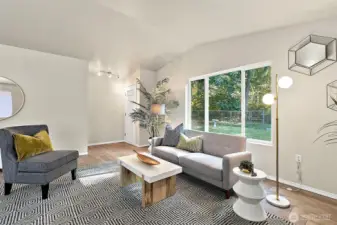 Large windows in the living room frame the tranquil backyard, filling the space with natural light and offering a calming connection to the outdoors.