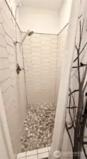 Primary bathroom boasts a tile shower w/stone floor