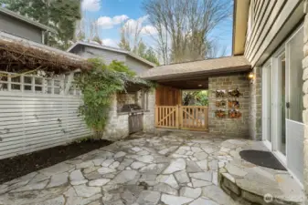 Side patio with BBQ area and gate to carport