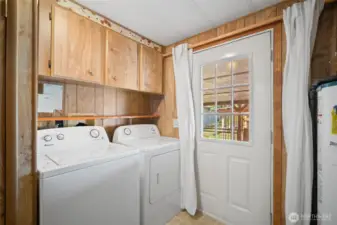 Utility room with full-size washer and dryer offers direct access to the back deck and yard.
