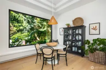 Stunning breakfast nook framed by a picture window with serene garden views and crafted trayed ceiling that adds depth and architectural interest.