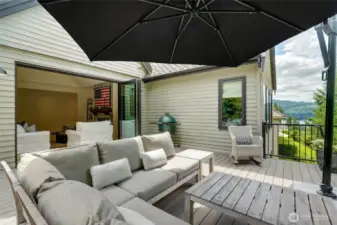 Spacious outdoor deck with scenic lake and treetop views, perfect for entertaining. Features seamless indoor-outdoor flow, lounge seating, and space for grilling or alfresco dining.