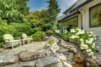 Tranquil garden retreat featuring a flagstone patio, and a serene cascading water feature—perfect for relaxing and enjoying your morning cup of coffee.