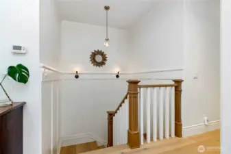 Elegant stair landing with custom millwork, wood and white spindle railing, and designer lighting—offering a bright and stylish transition between levels.