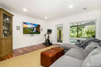 Versatile lower-level bonus room with large windows, custom millwork, built in surround sound and space for media, fitness, or relaxation—offering flexible living with direct outdoor access.