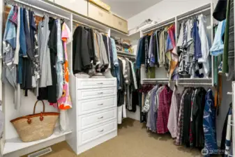 Spacious walk-in closet with custom built-ins, abundant hanging space, and integrated drawer storage—designed for optimal organization and functionality.