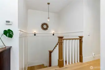 Elegant stair landing with custom millwork, wood and white spindle railing, and designer lighting—offering a bright and stylish transition between levels.