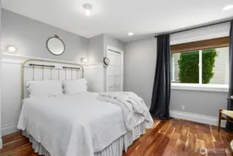 Charming first guest bedroom on the lower level featuring warm hardwood floors, classic wainscoting, and ample natural light—ideal for visitors or flexible living space.