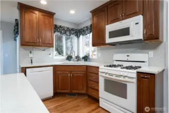 Warm beech wood cabinetry pairs beautifully with quartz countertops and a gas range, creating a kitchen that is both stylish and functional.
