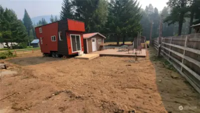 Another view of the tiny home and bunkhouse with the expansive deck and the outbuilding beyond that houses about $5000 worth of building materials that transfer with the sale.