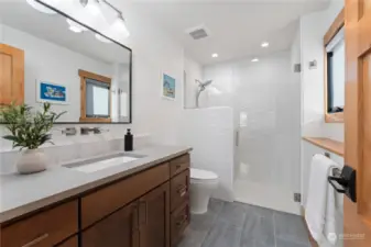 Main level guest bedroom w/ on-suite bathroom w/ ceramic tile floors, quartz countertops and tiled shower.