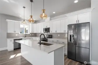 A chef’s dream kitchen featuring custom cabinetry, gleaming quartz countertops, beautiful appliances, and designer lighting