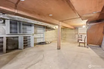 Oversized unfinished basement with storage and shelving.