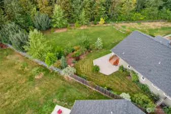 View of the side yard and large patio off the back deck. Plenty of room for a garden, and there is a fruit bearing pear tree as well.
