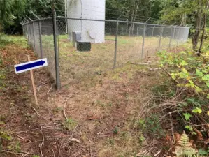 Your water comes from here. Easement road is on the far side of the fence. Walk down it until you get to neighbor's gate and then continue down the hill until you come to the stairs.