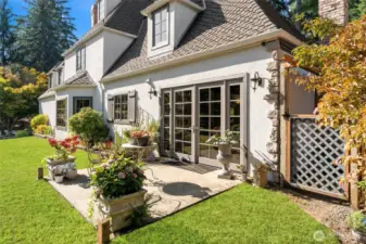 Mature garden beds and fenced area on side of house for waste bins.