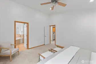 Primary bedroom with high ceiling and direct access to the attached bathroom. Carpeted flooring and neutral tones create a bright and versatile space.