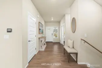 Entryway looking toward the front door, garage to the left. Powder bath and office to the right.