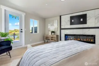 Primary bedroom with it's own cozy fireplace + a view of the lake.