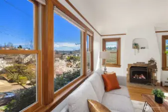 Gorgeous living room with newly finished oak hardwood floor and a inviting wood fireplace, with sweeping views of Cascades, Mt Rainier, the Ship Canal bridge and surrounding areas