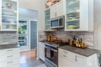 This modern kitchen is to live for! Custom cabinets with wavey glass, gorgeous tile backsplash, 6-burner propane stove top, soft-close cabinets and more!