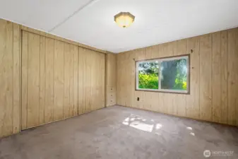 Bedroom with a wide closet and built-in drawers, filled with natural light from the large window.