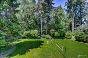Spacious and level backyard with mature plantings.