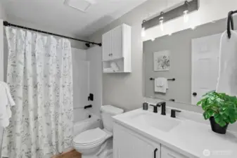 Pretty Hall Bathroom with quartz topped vanity, large mirror, toilet and tub/shower combo!