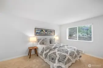 The primary bedroom offers plush new carpet, a wide picture window for afternoon light, and direct access to a full, updated bath—one of two refreshed bathrooms in this two-bed home.
