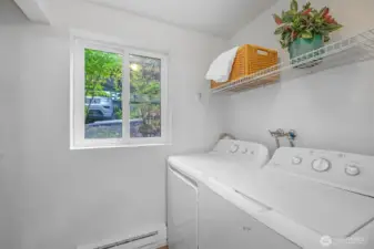 Dedicated laundry room with full-size washer and dryer, daylight window, and overhead shelving keeps chores tucked away and adds valuable utility rarely found in condo living.