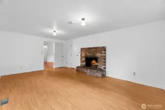 Family room with view of wood burning fireplace. Door to garage is to left of fireplace. Living room (next to kitchen) is visible as well!