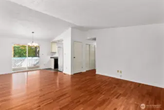 Living room facing kitchen, dining area, sliding glass doors to rear covered deck, and hallway. Hallway features coat closet and spacious linen closet.
