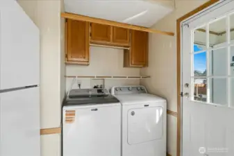 Utility room with second refrigerator and mudroom access.