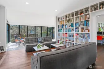 The stately living room features handsome wide plank engineered hardwood floors and floor-to-ceiling bookcases.