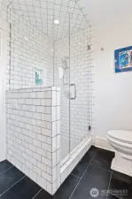 Modern shower with clean subway tiles and glass enclosure.