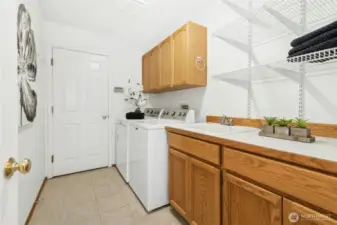Utility room with a sink, cabinets and counter top. Door leads out to the large 3-car garage.