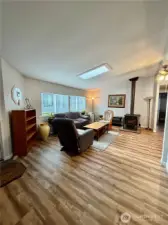 Spacious living room area with skylight and wood burning stove.